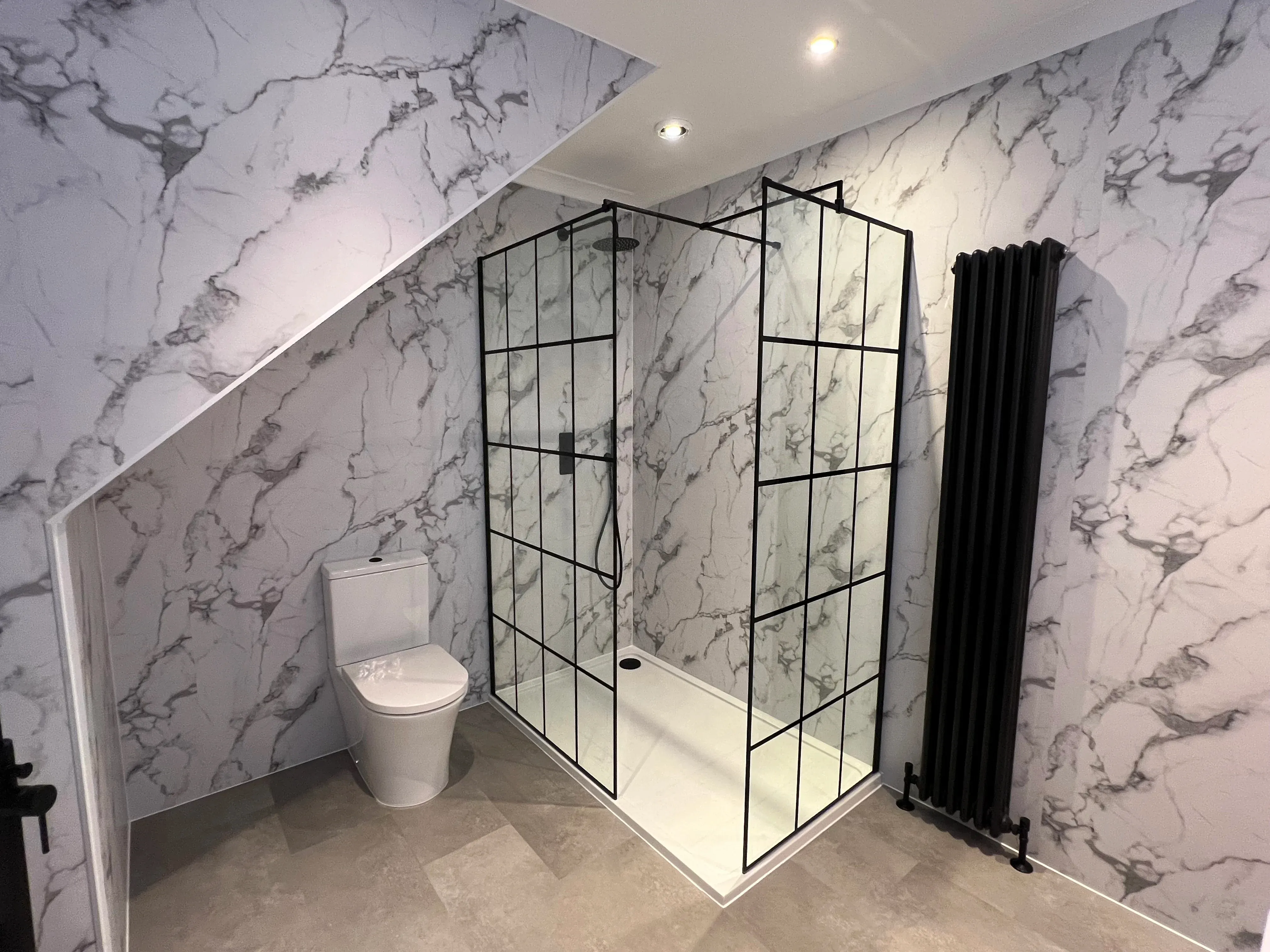 Bathroom fitting in Essex with marble-effect walls and a glass shower enclosure