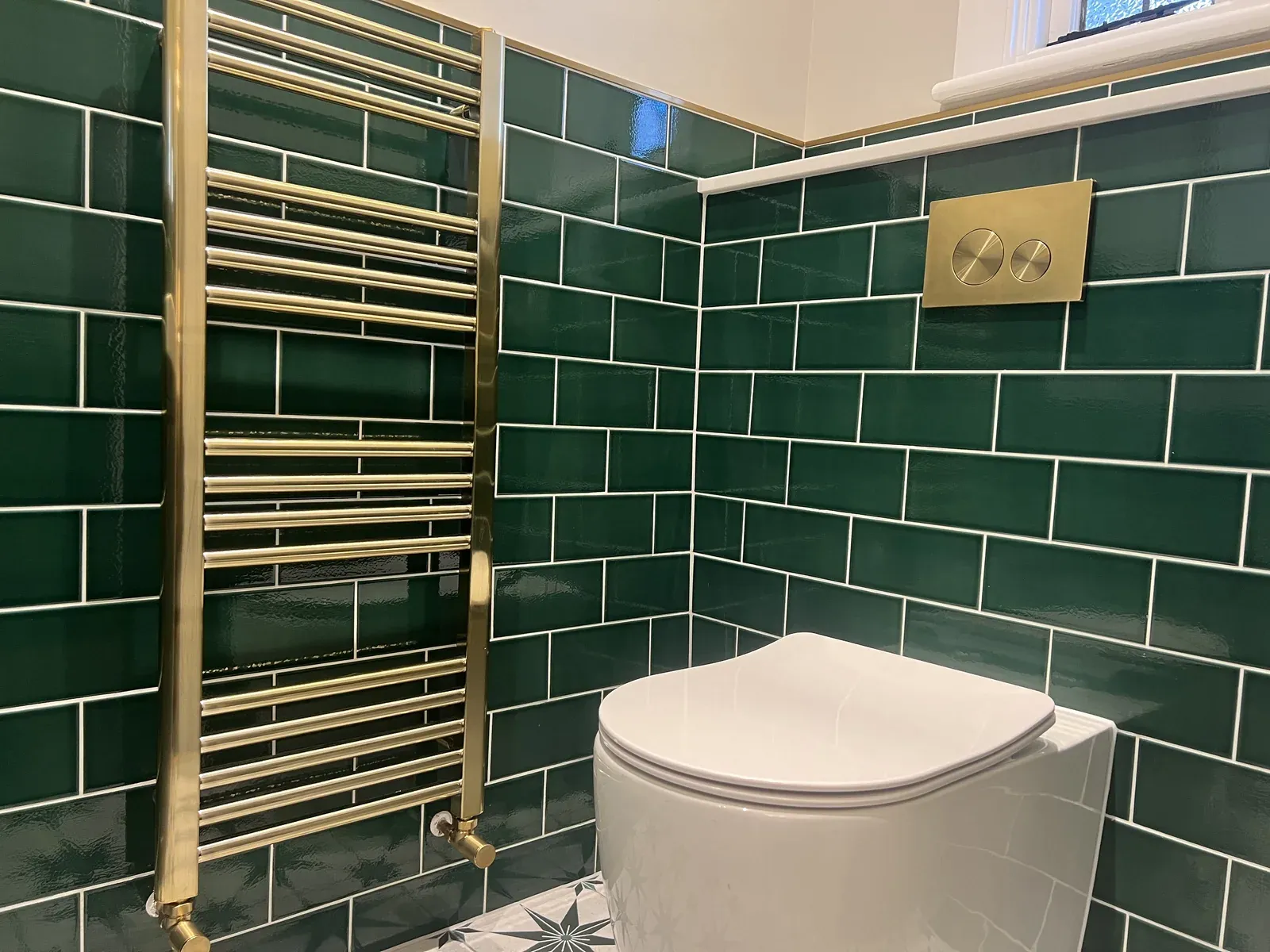 Finished green-tiled bathroom with toilet and heated towel rail in Gidea Park