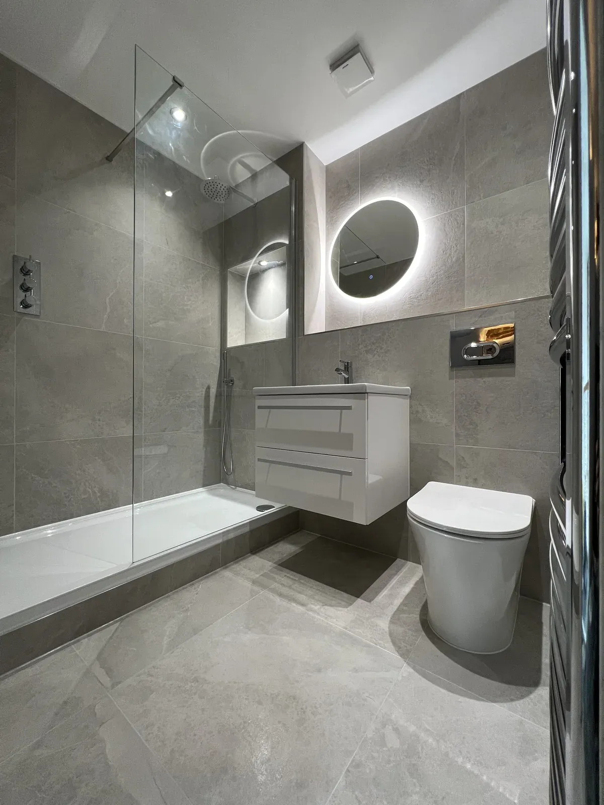 Completed grey-tiled bathroom with shower, vanity and toilet in Harold Wood